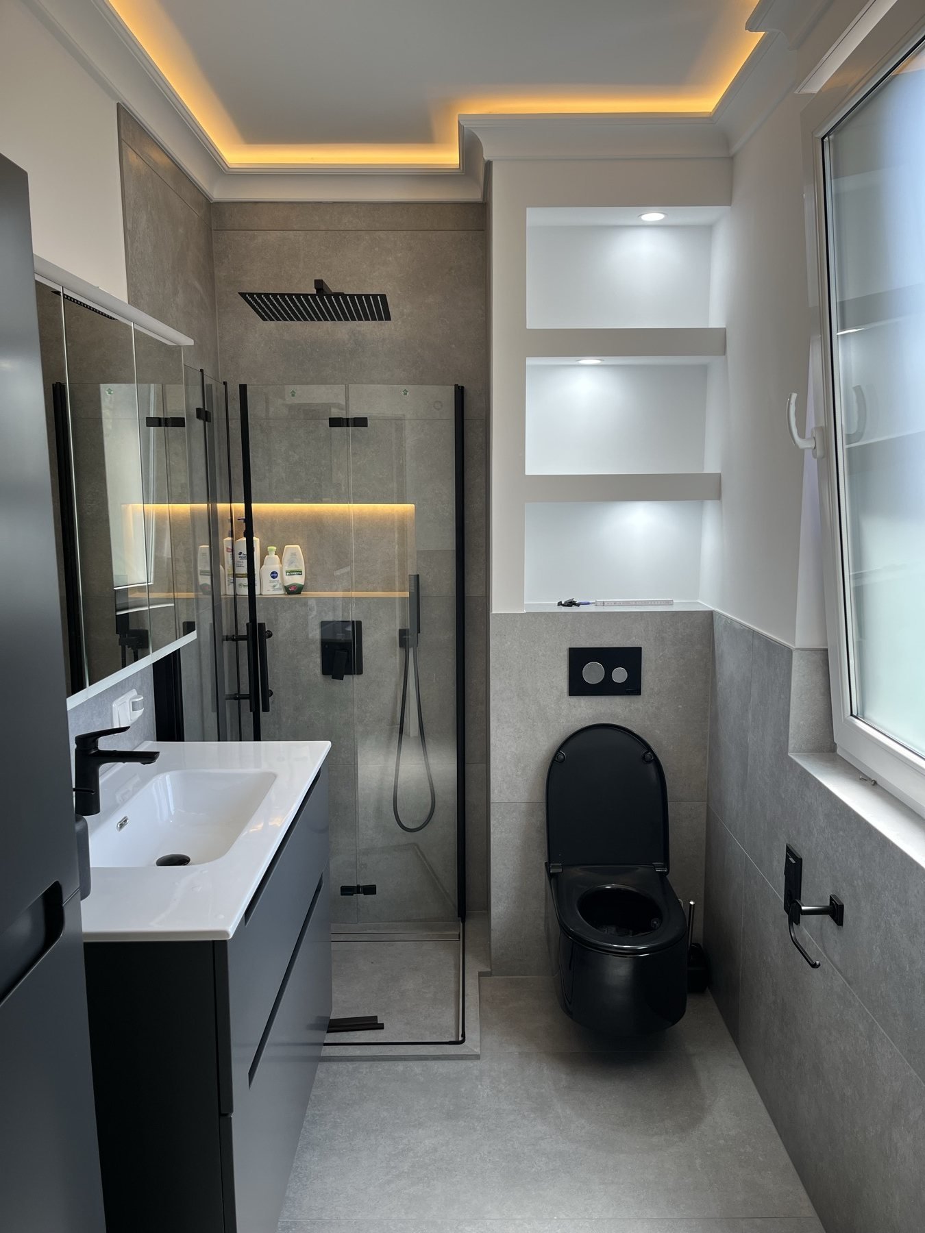 Bad mit schwarzen Armaturen und beleuchteten Wandfächern