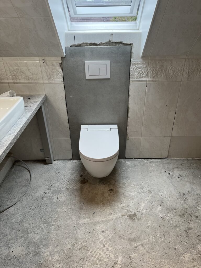 Wand-WC neben einer gefliesten Badewanne