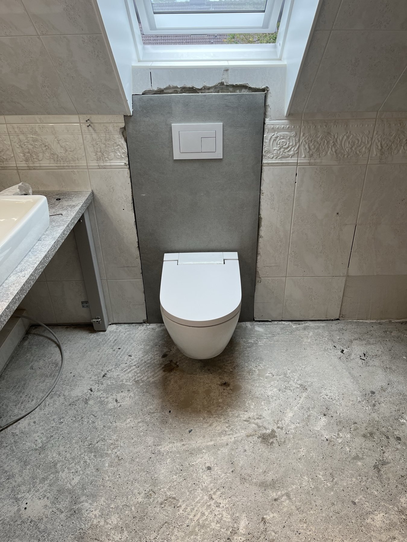 Wand-WC neben einer gefliesten Badewanne