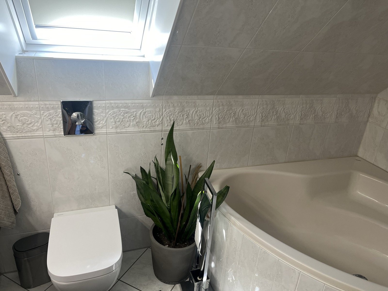Heller Badbereich mit Badewanne und Dachfenster