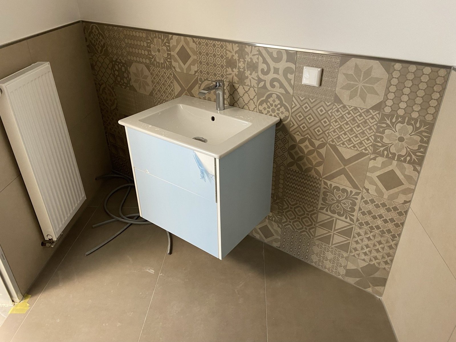 Waschbecken vor einer gemusterten Fliesenwand
