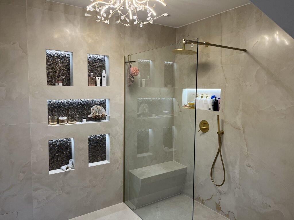 Dusche mit beleuchteten Mosaiknischen und goldfarbenen Armaturen