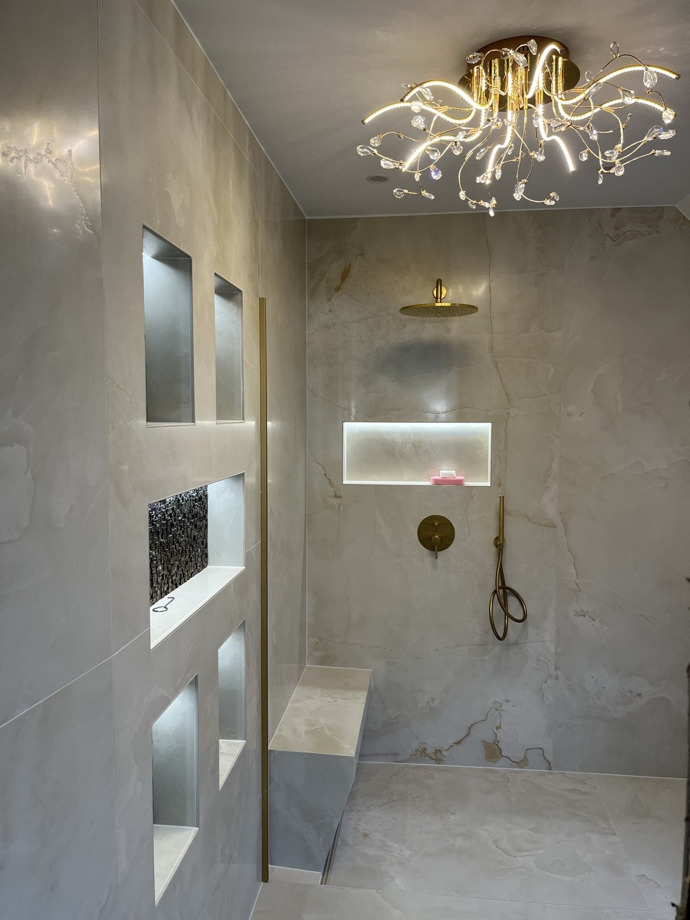 Badezimmer mit beleuchteter Nischenwand und Kronleuchter