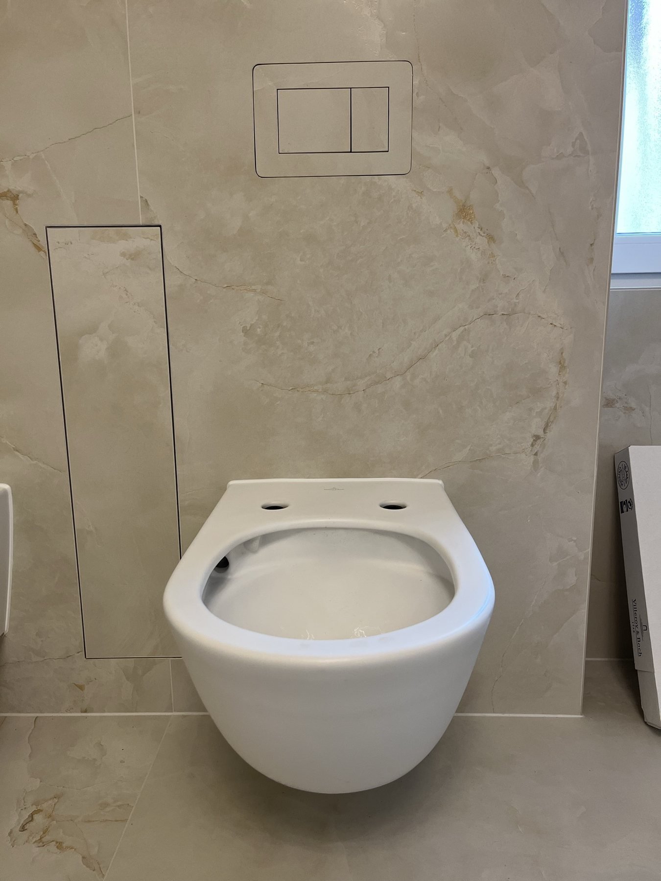 Wand-WC vor hellen Fliesen in Steinoptik